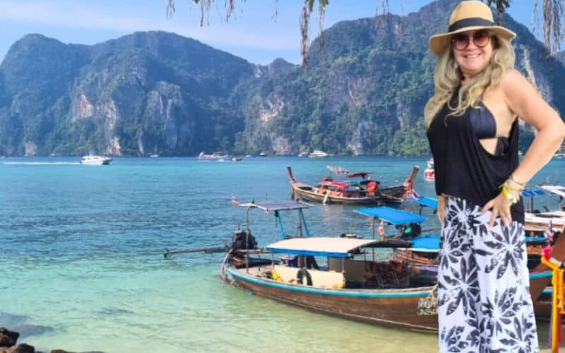 Olivia na Tailândia com barcos no mar ao fundo